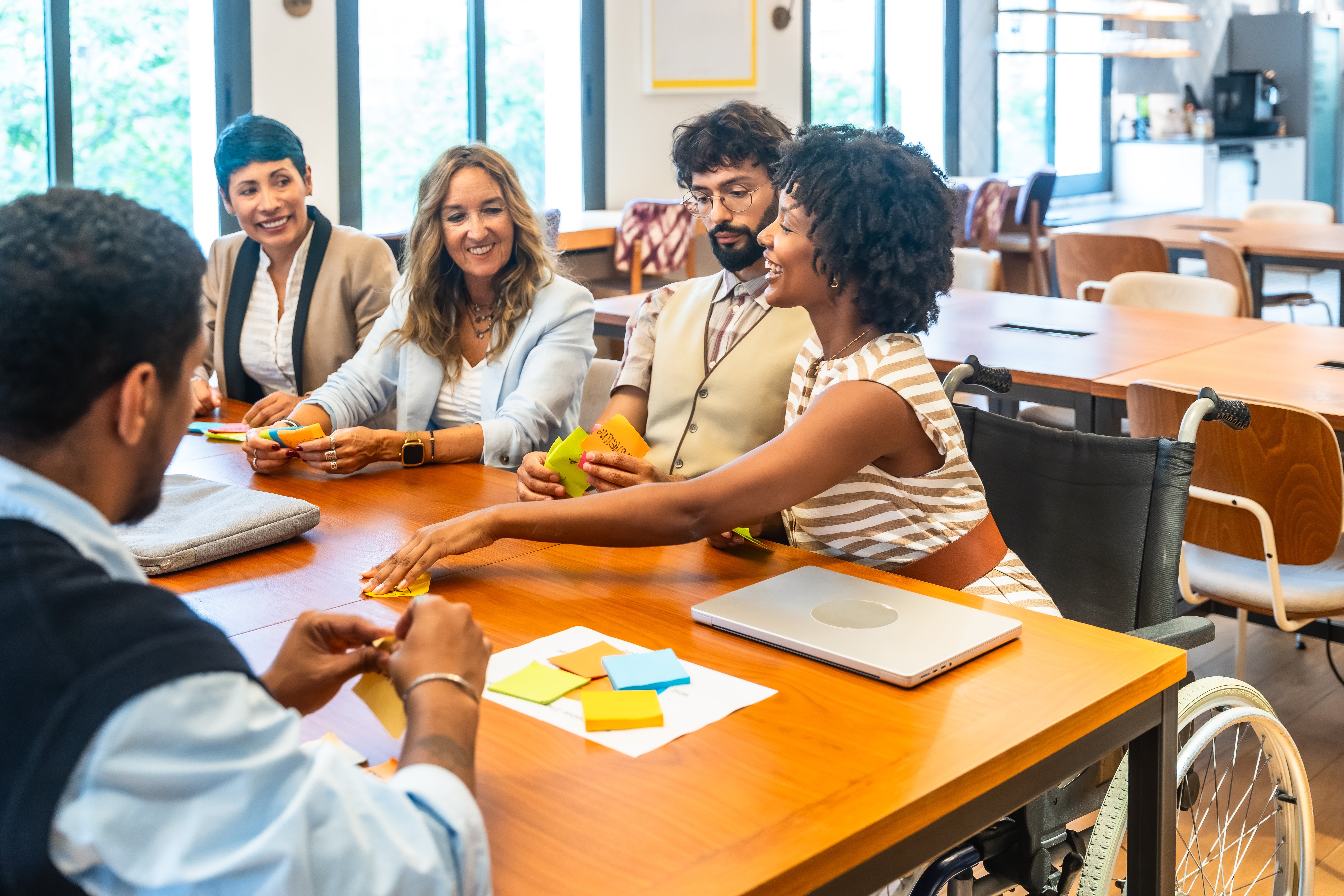 Diverse business colleagues holding a productive meeting in a modern coworking office, actively collaborating and brainstorming ideas with colorful sticky notes